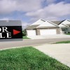 House on suburban street with 'For Sale' sign in foreground --- Image by © Royalty-Free/Corbis