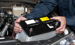 Auto mechanic replacing car battery